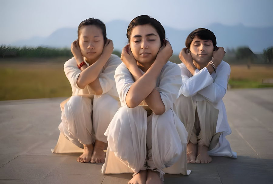 Three practitioners in Thoppukarnam squat with arms crossed
